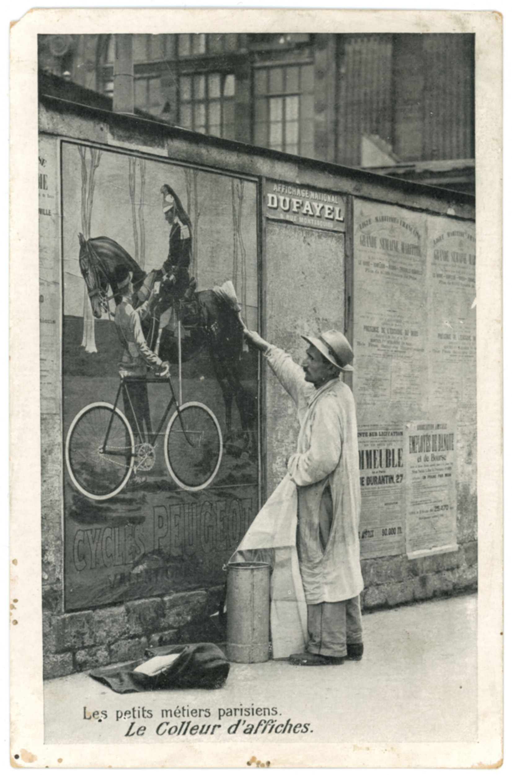 Schwarzweiß-Postkarte: Ein Mann in Arbeitskleidung klebt ein großes Plakat an eine Pariser Werbewand. Dazu der Schriftzug „Les petits métiers parisiens – Le Colleur d’affiches.“