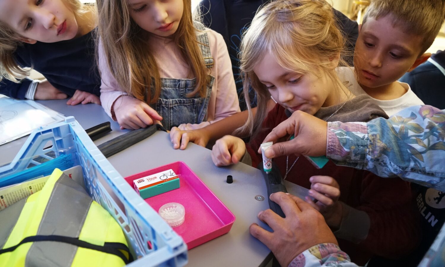 Kinder arbeiten gemeinsam an einem Tisch mit Flickutensilien und einem Werkzeugkasten.