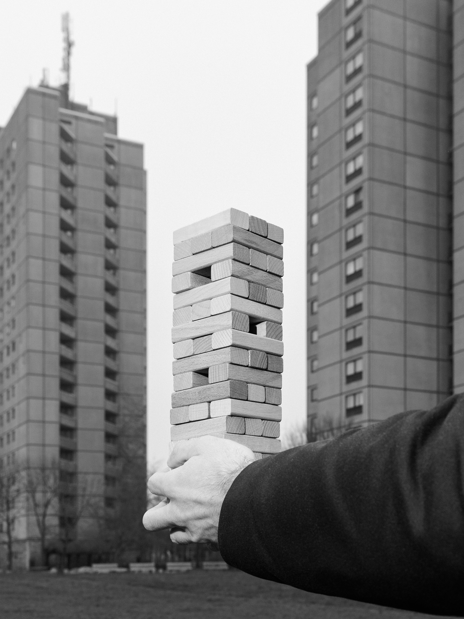 Eine Hand hält einen Stapel von Holzklötzen vor dem Hintergrund von Hochhäusern.