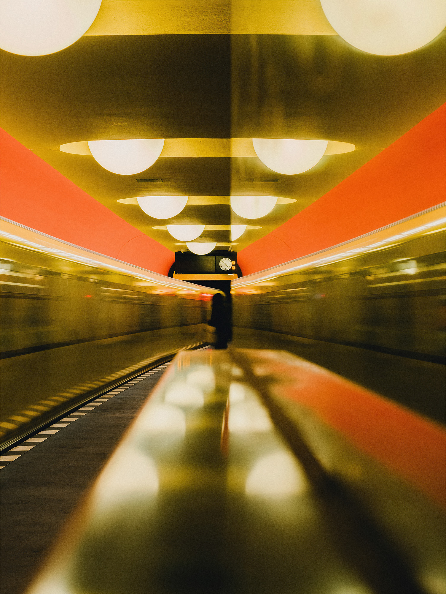 Ein verschwommener Blick auf eine U-Bahn-Station mit Lichtern, einer Anzeige und einer Uhr an der Decke.