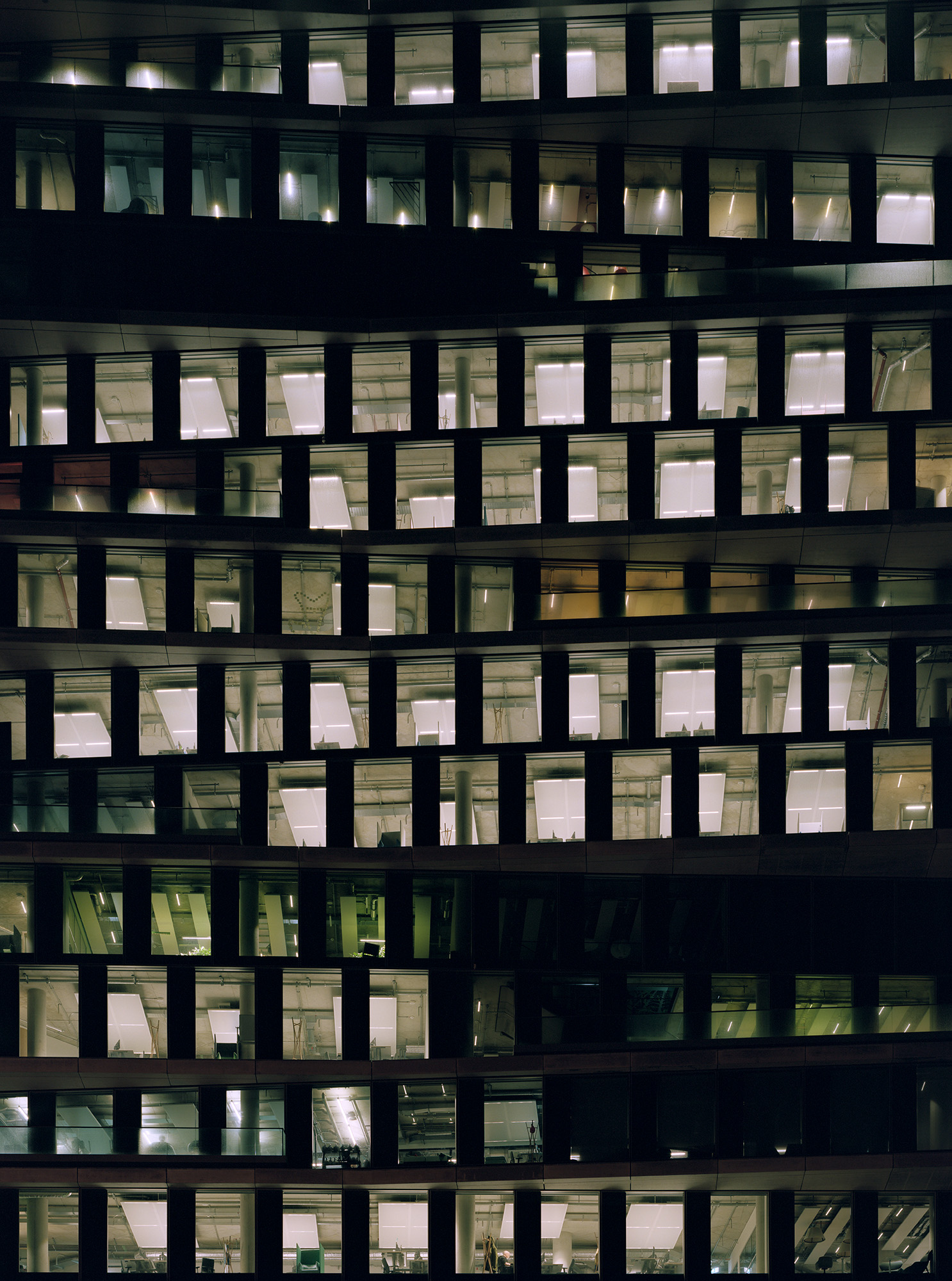 Ein Hochhaus mit vielen beleuchteten Fenstern in der Nacht.