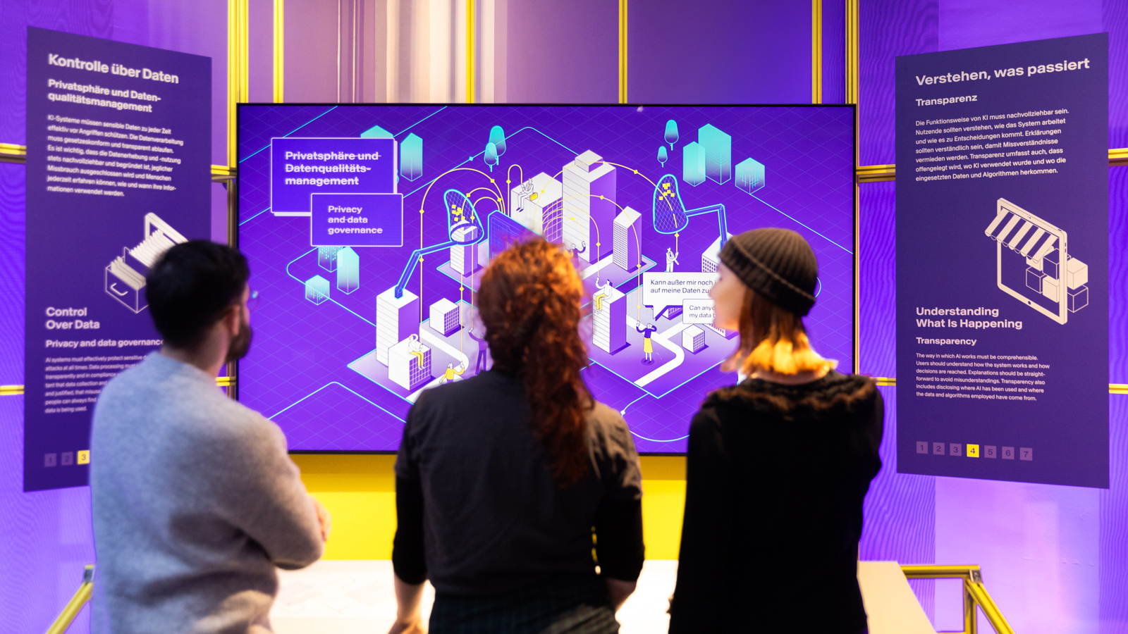 Drei Personen betrachten eine Ausstellung über Datenschutz und Datenqualitätsmanagement mit Erklärungen zu Kontrolle über Daten und Transparenz.