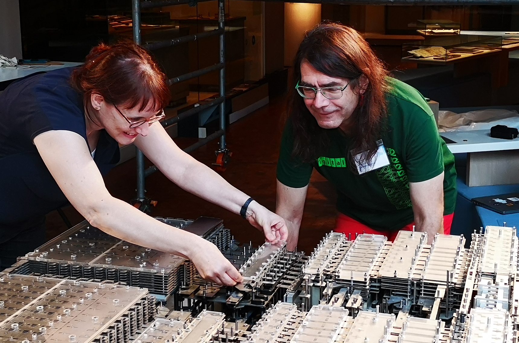 Zwei Personen sind über den Nachbau des Z1-Computers gebeugt. Eine Person entfernt vorsichtig ein Bauteil.