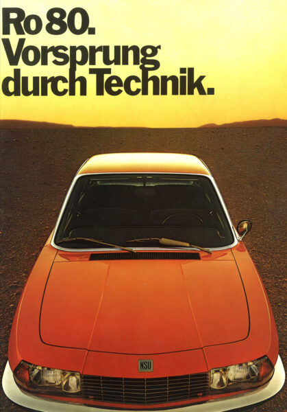 Vorderansicht eines NSU Ro 80 mit dem Slogan "Vorsprung durch Technik" vor einer Wüstenlandschaft bei Sonnenuntergang.