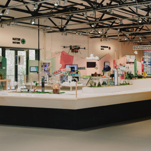 Ausstellung mit Stadtmodellen, einer Drohne, Infotafeln und dem Motto "Bau mit an unserer Stadt der Zukunft! / Help us build our city of the future!"