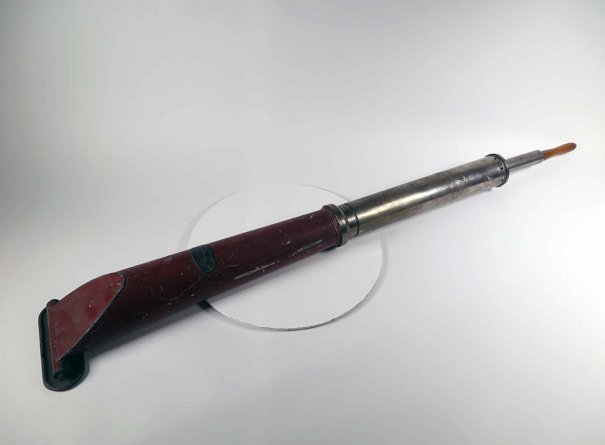 Historischer Handstaubsauger mit Holzgriff und Metallrohr auf weißem Hintergrund.