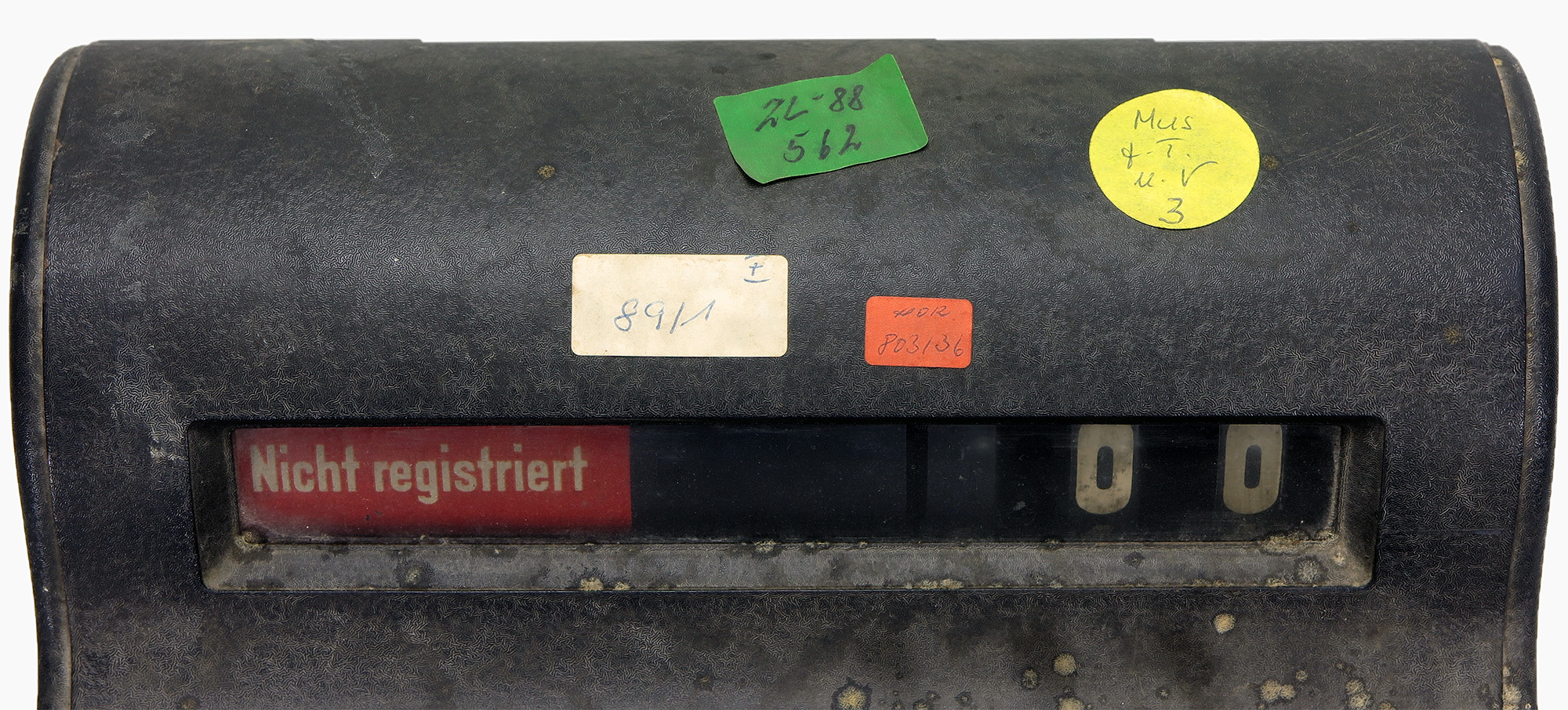 Alter mechanischer Kassenapparat mit der Anzeige ‚Nicht registriert‘ und Aufklebern mit Inventarnummern.
